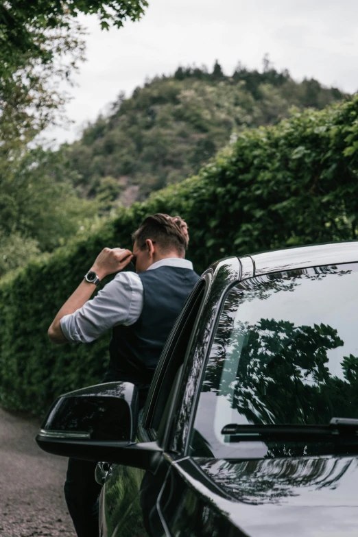 a person leaning out the window of a car and wearing a vest