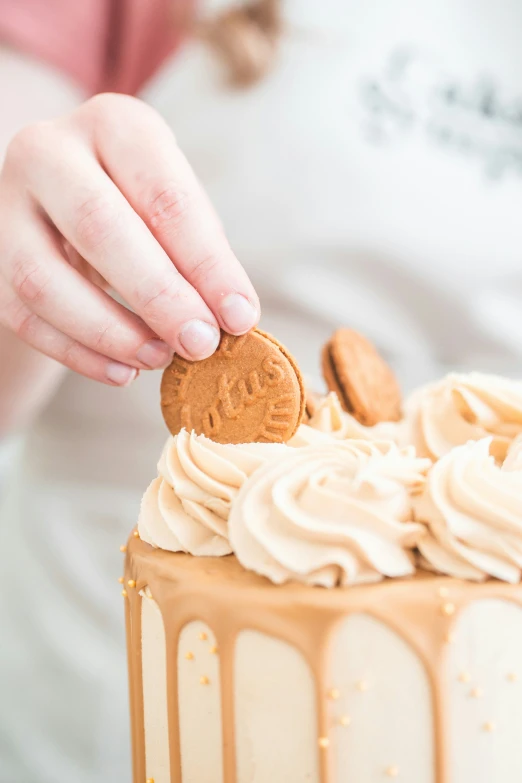 the person is putting a cookie on the frosting