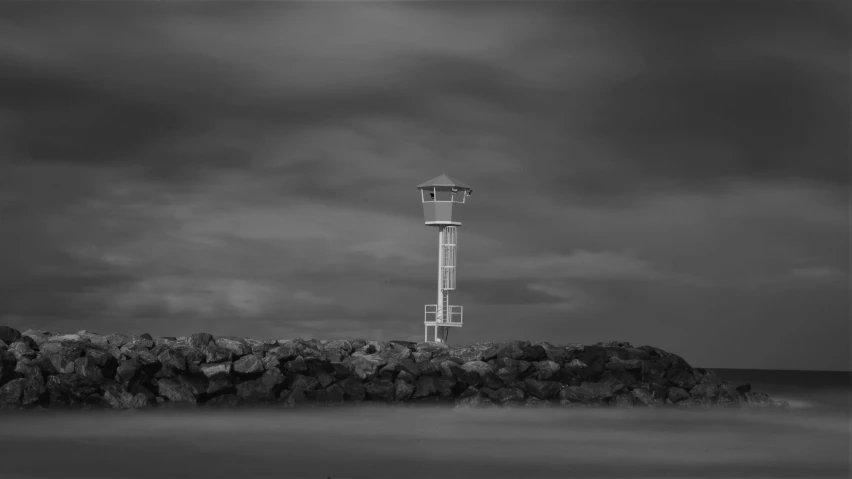 an old light house on the ocean with dark clouds