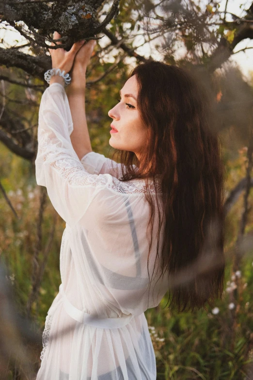 a woman is holding onto the nches of a tree