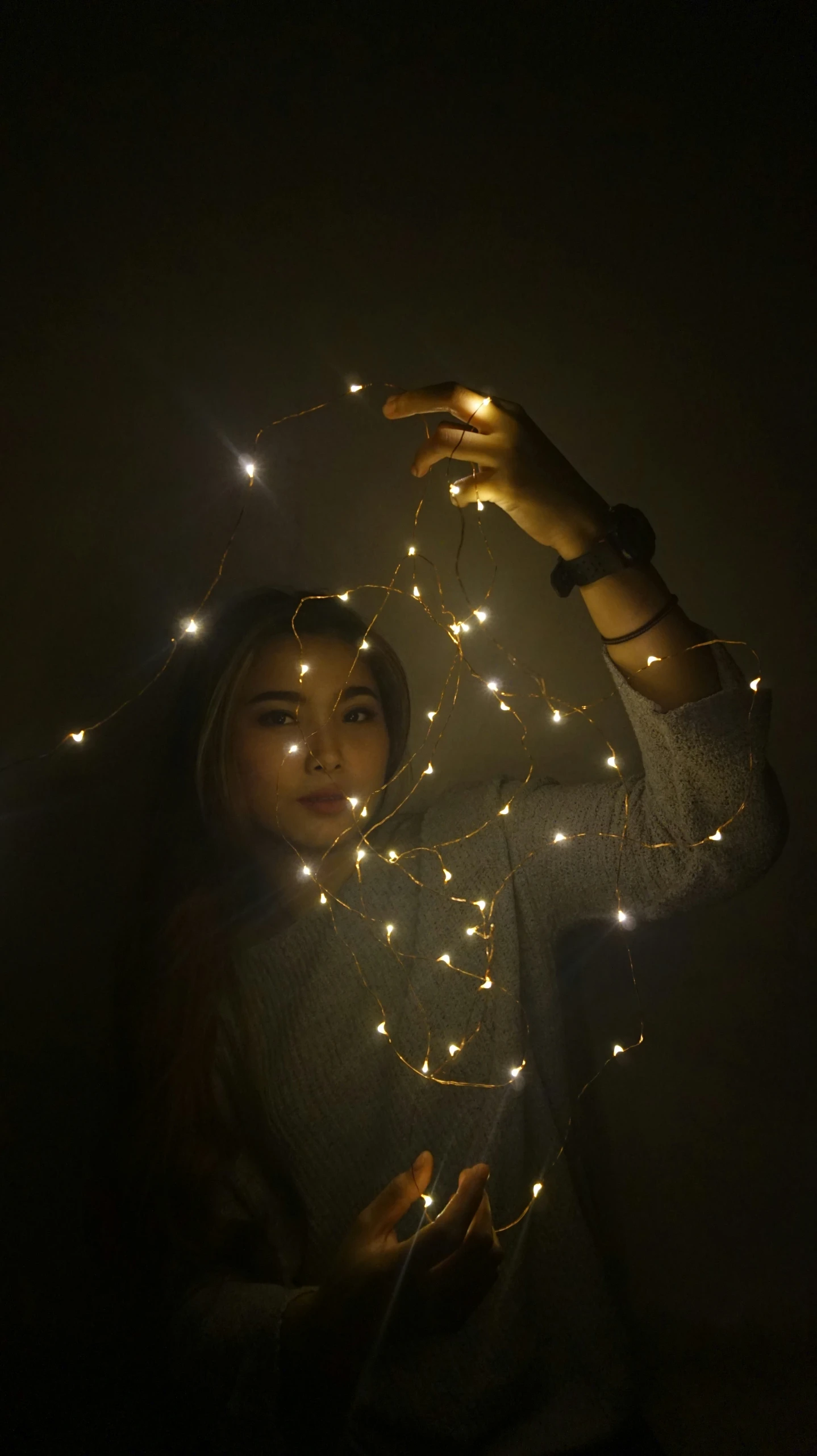 a woman with string lights around her fingers