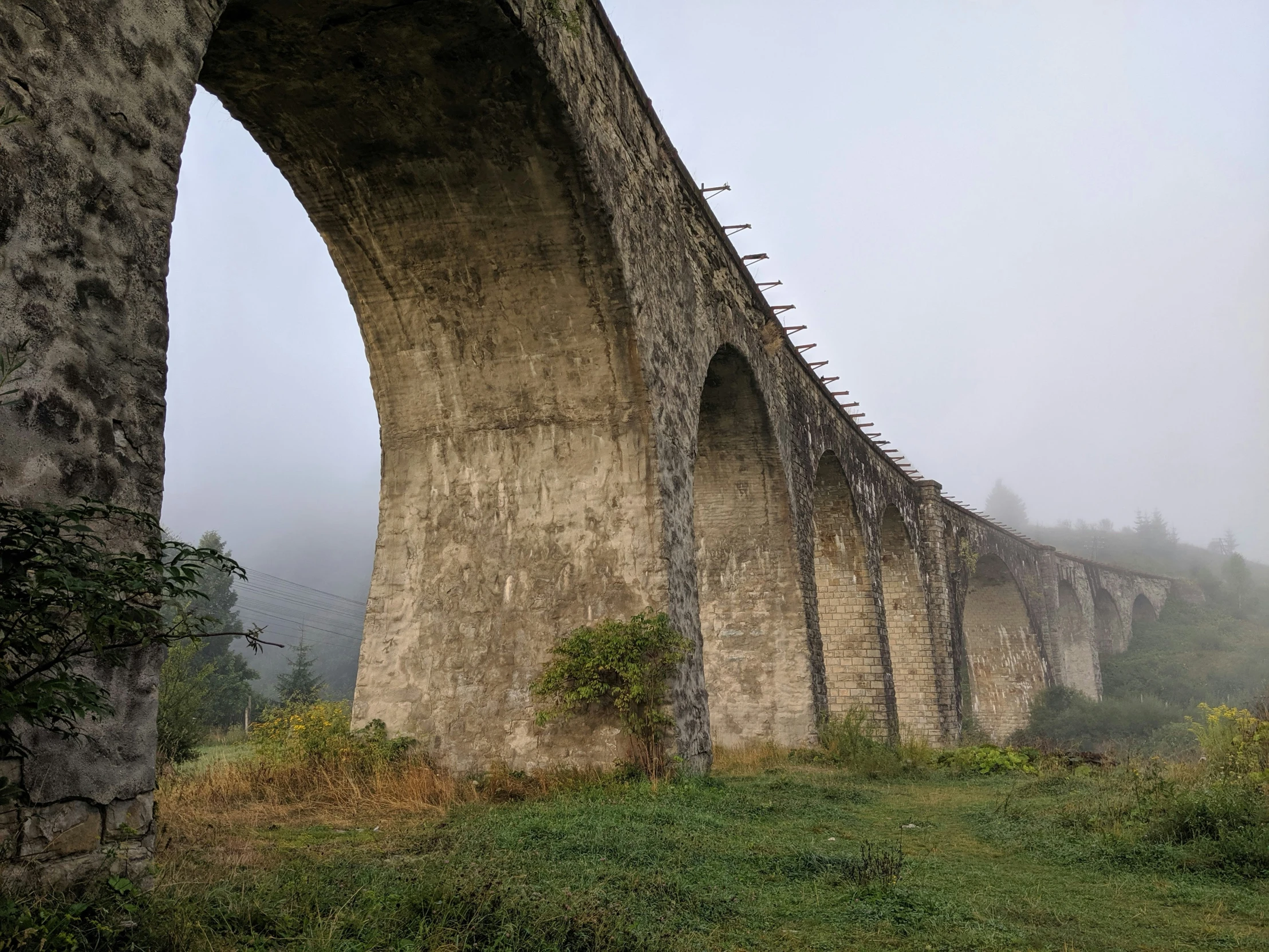 a long stone bridge over a river on a foggy day