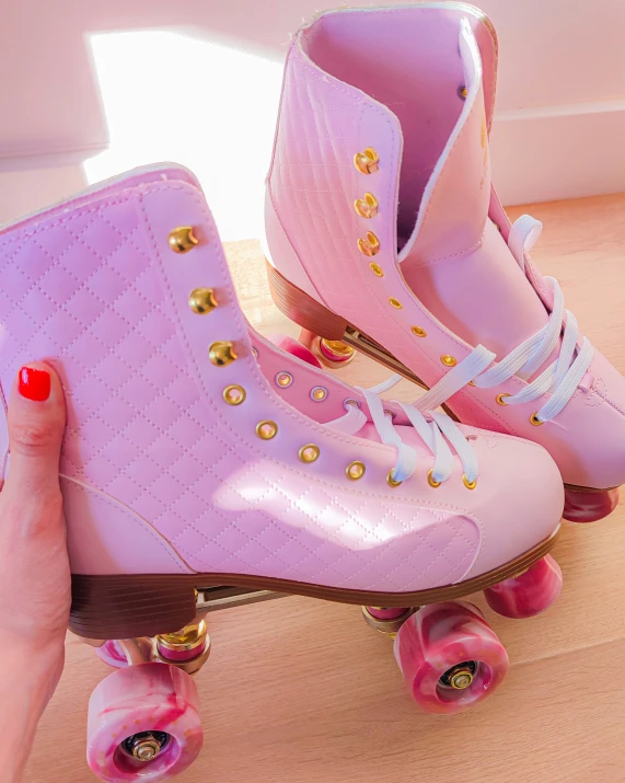 someone is holding the pink roller skate with gold accents