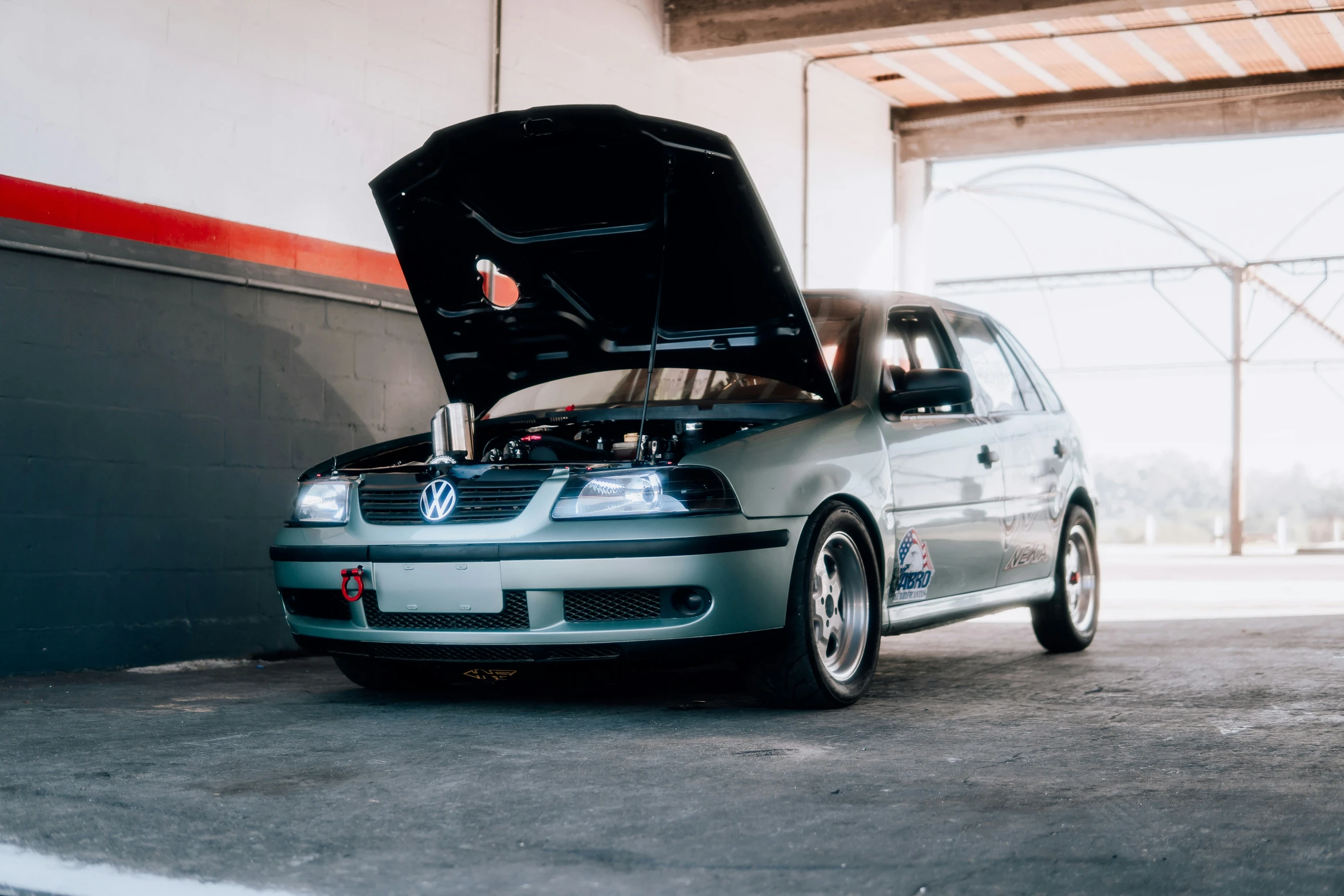 a blue car is in a garage and a person is under the hood of the vehicle