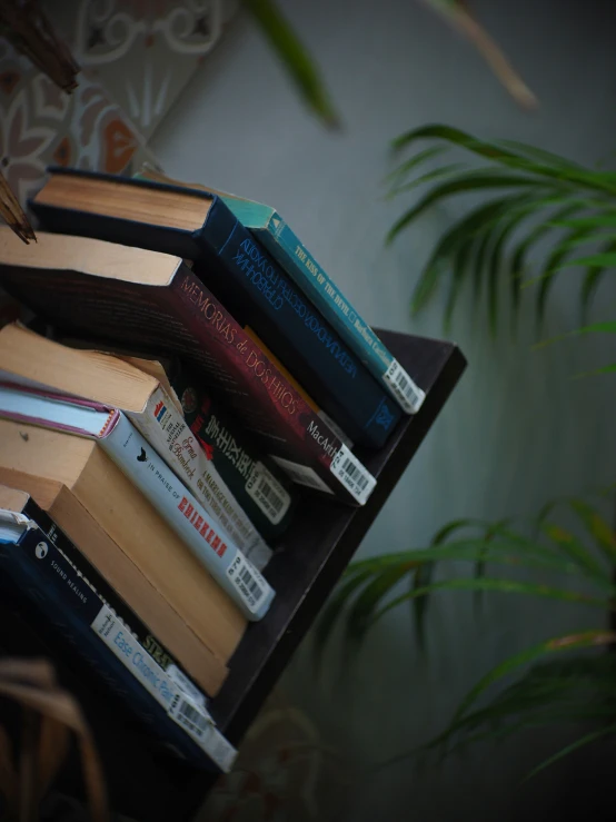 an arrangement of books are stacked on a stand