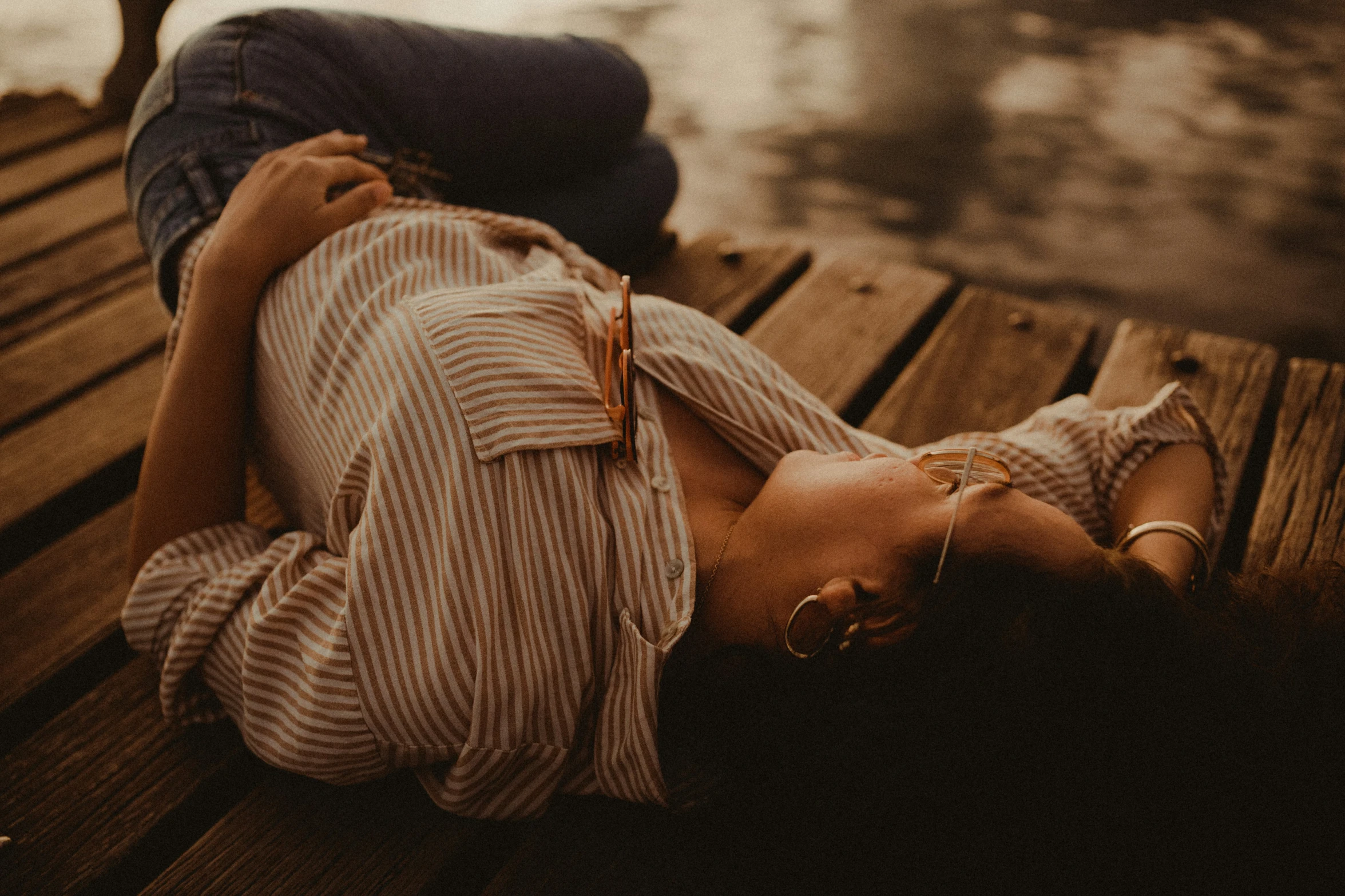 a woman sitting on the side of a wooden dock