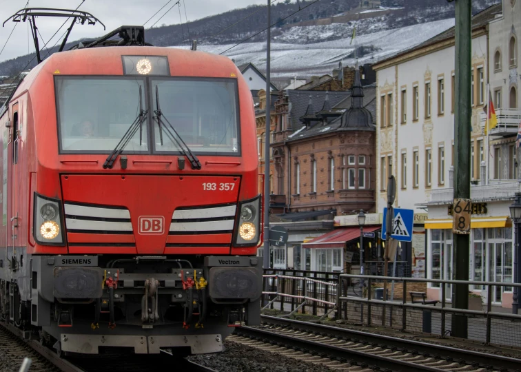 a red and white train on the tracks near buildings