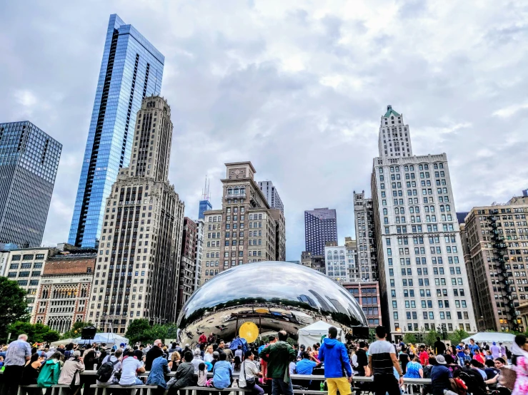 a crowd of people are gathered together under the silver balloon