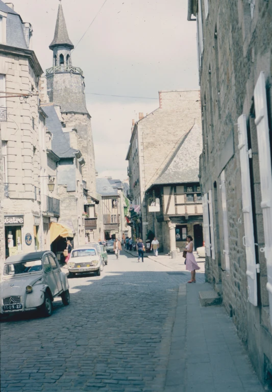 a small white car driving down a street next to tall buildings