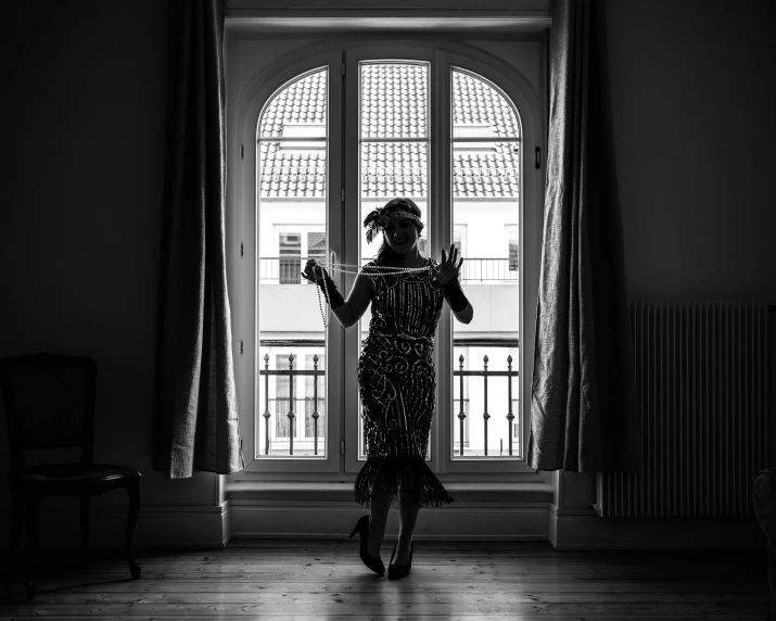 black and white pograph of a woman standing by a window