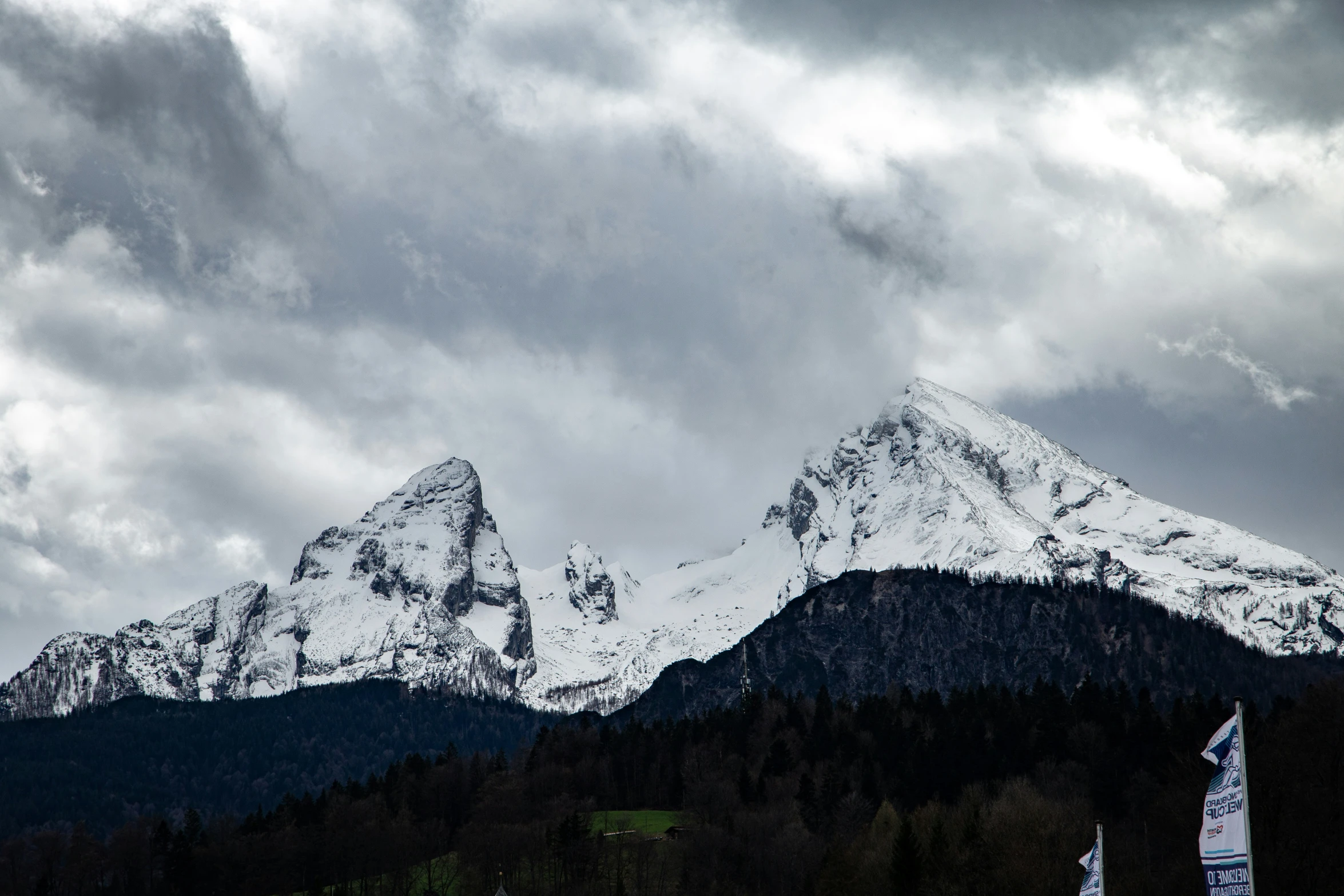 a snow capped mountain is seen against a cloudy sky