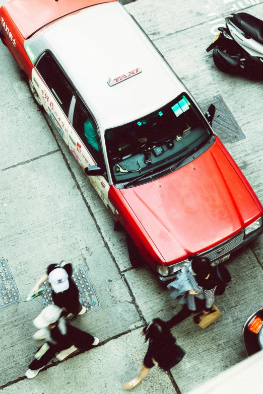 a red car is stopped next to a couple of women walking