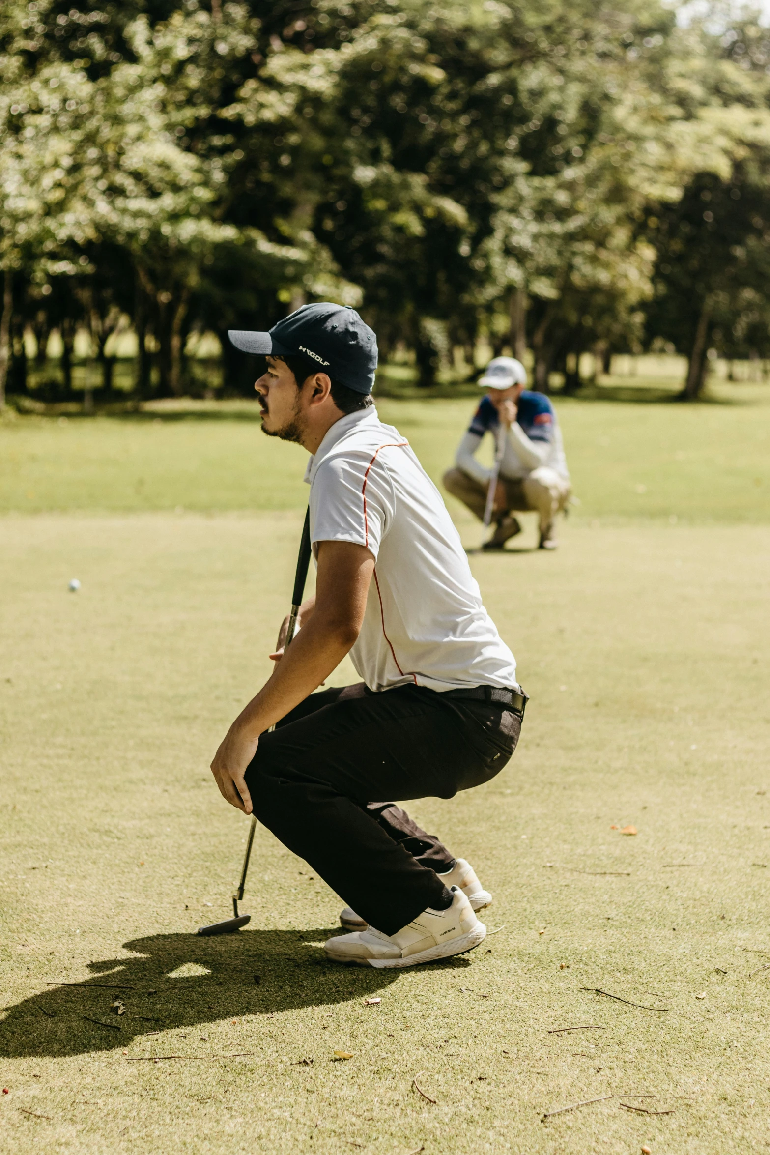 a man bent over playing golf while another man watches