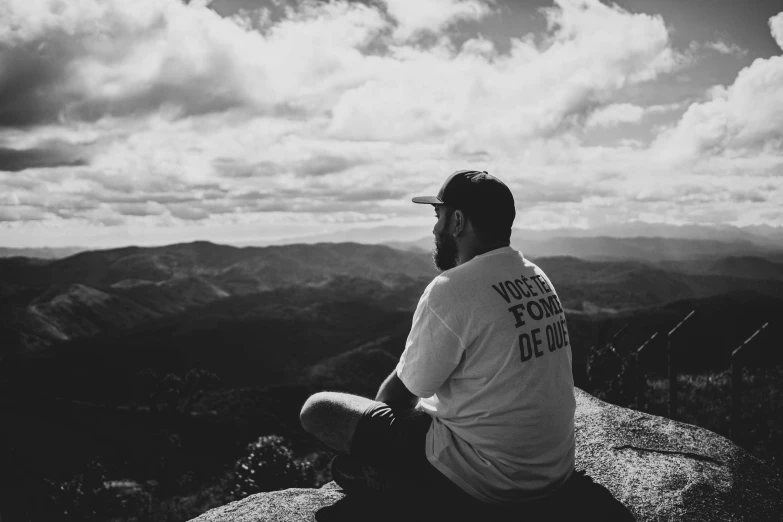 black and white pograph of man sitting in the wilderness