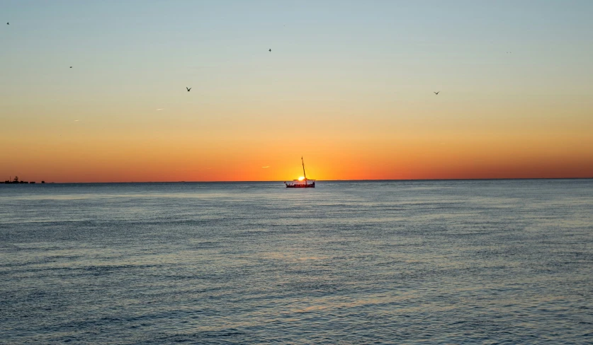 a boat sails out into the distance in the sunset