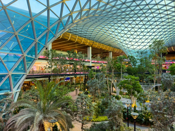 a very large atrium with tall roof plants and people walking