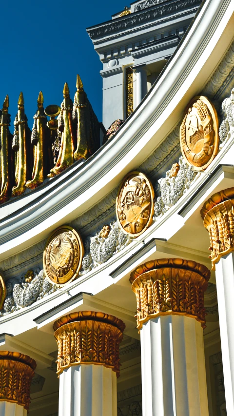 some ornate gold decorations hang on the side of a building