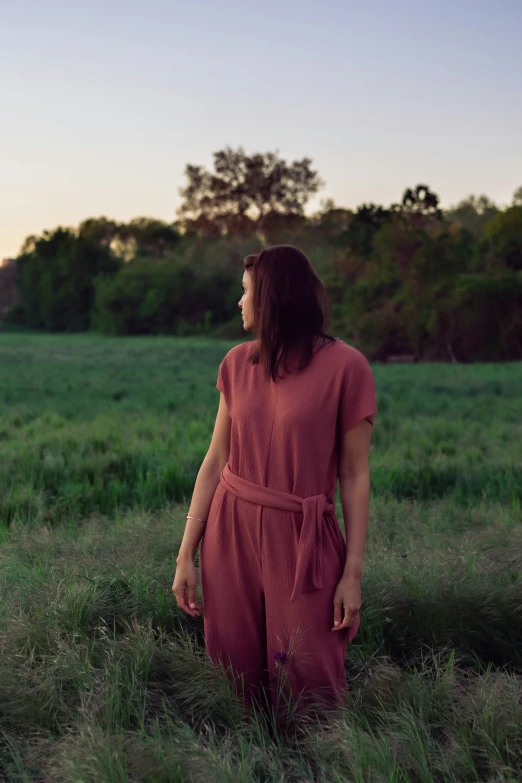 a woman in an open field during sunset