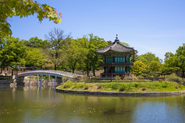 a pond with some trees and a bridge in it