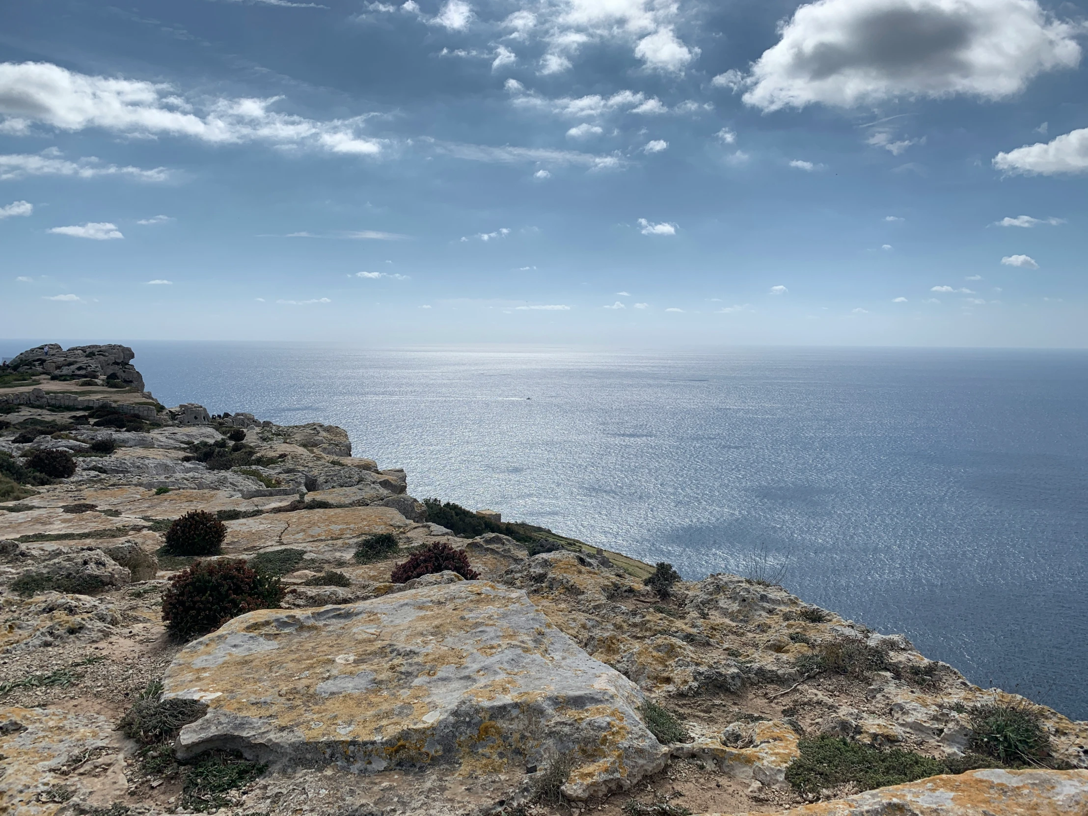 a cliff sitting next to the ocean with lots of rocks