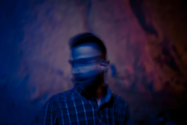 man wearing a plaid shirt standing in the dark