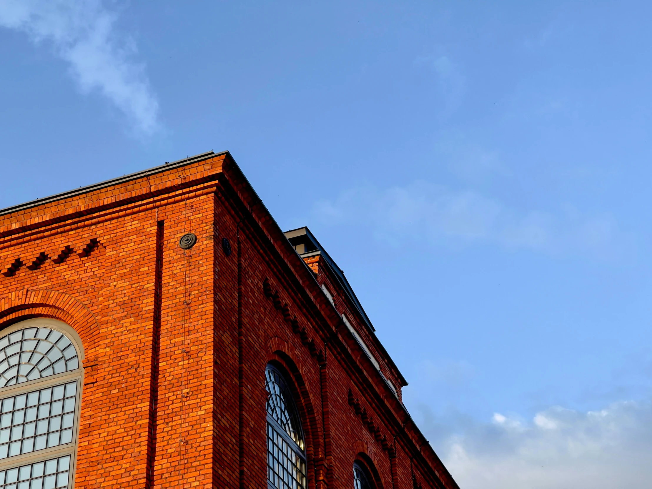 a tall building has two windows, and a clock on it