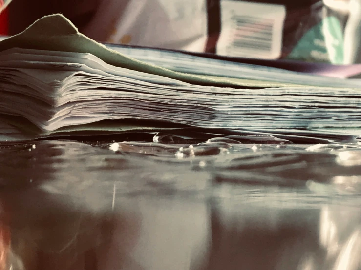 stack of magazines and papers on table with water droplets