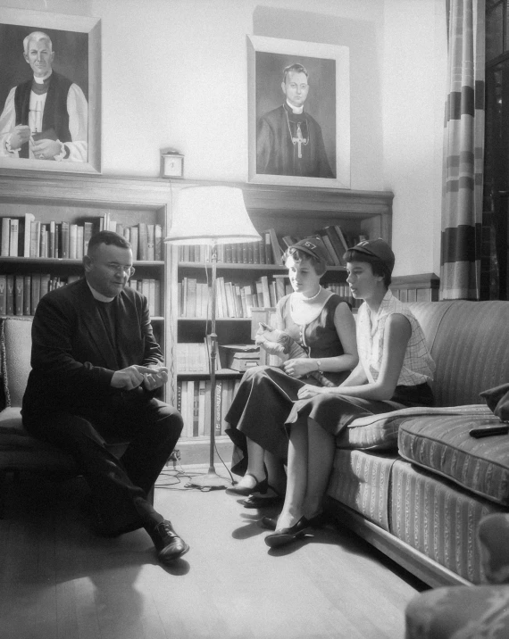 a woman sitting on the couch with a boy watching her on a computer