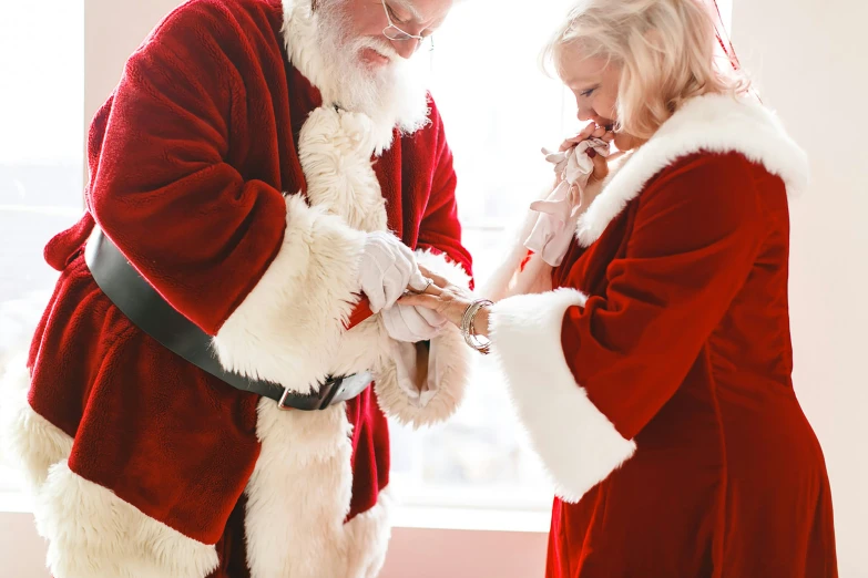 a santa clause is putting a ring on a girl's finger