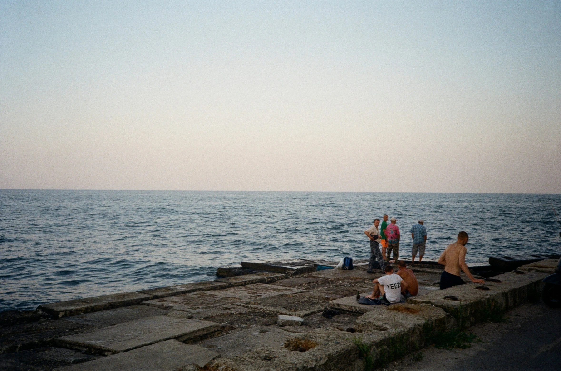 people hanging out on a jetty near the ocean