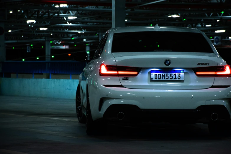 the back end of a white car parked in a parking garage