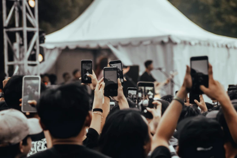 a large group of people taking pictures with their cell phones