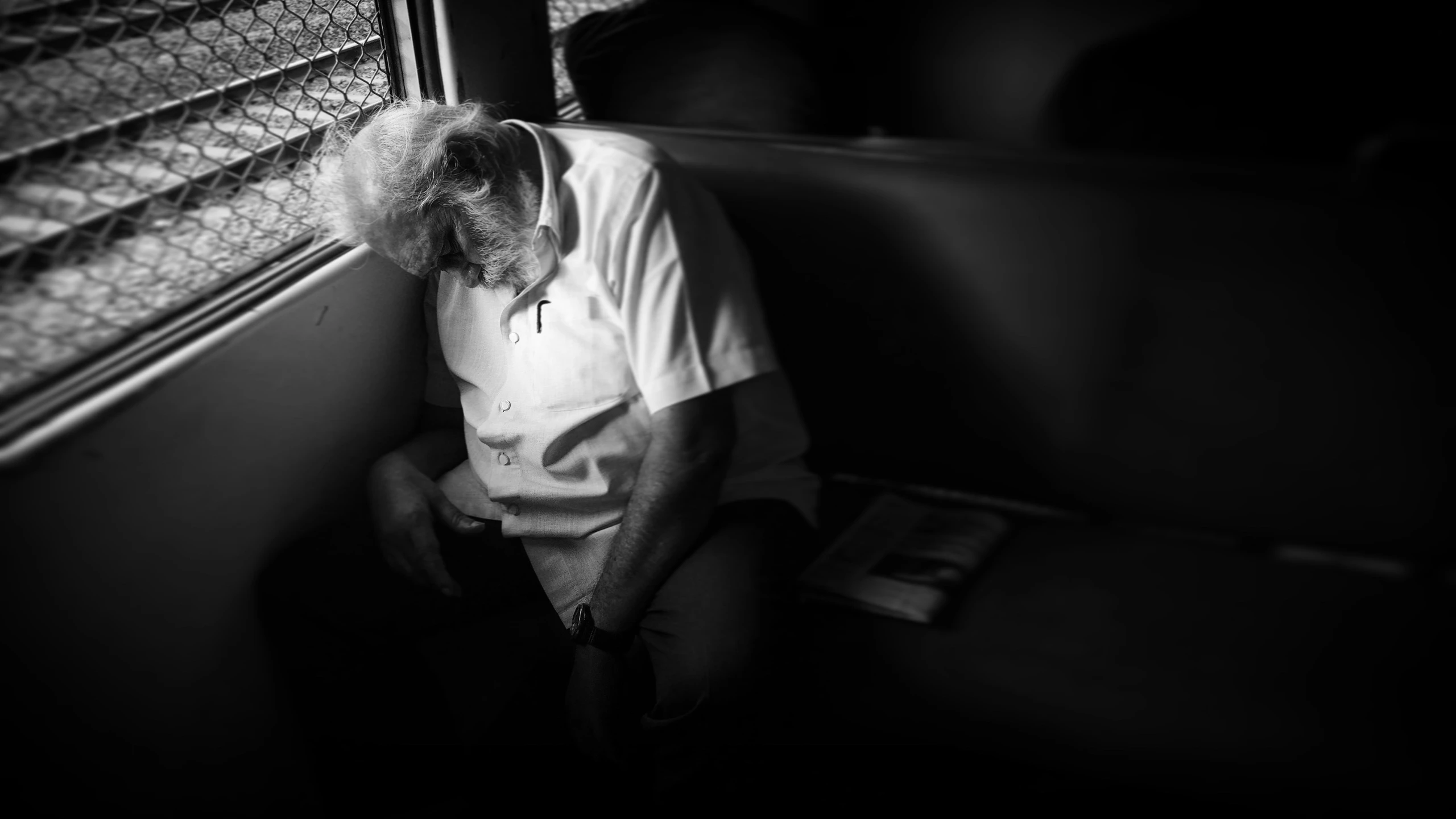 an old man sitting on a bus in the dark