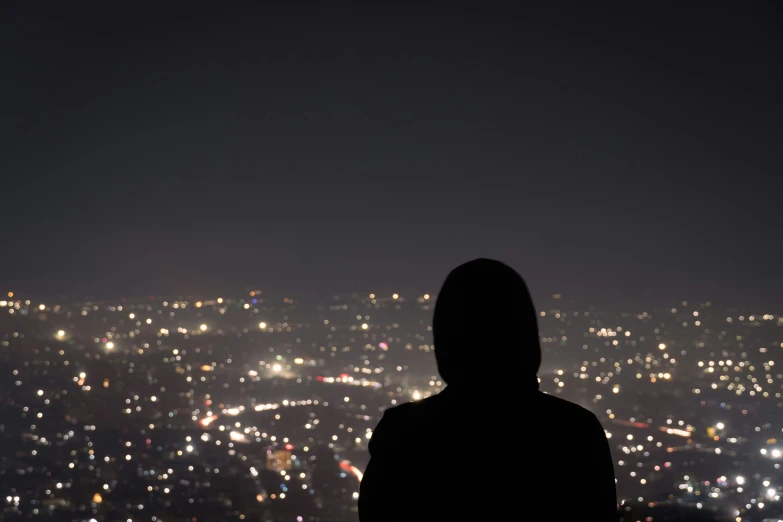 person standing in front of large cityscape at night