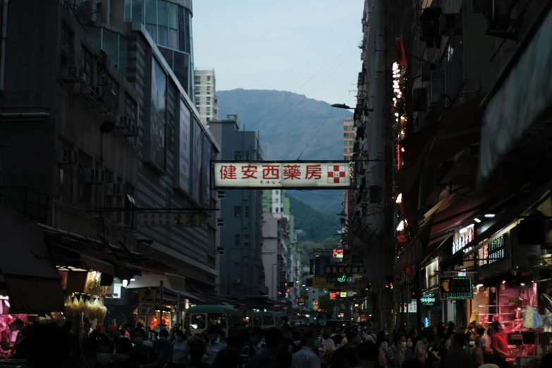 street crowded with pedestrians and signs at dusk