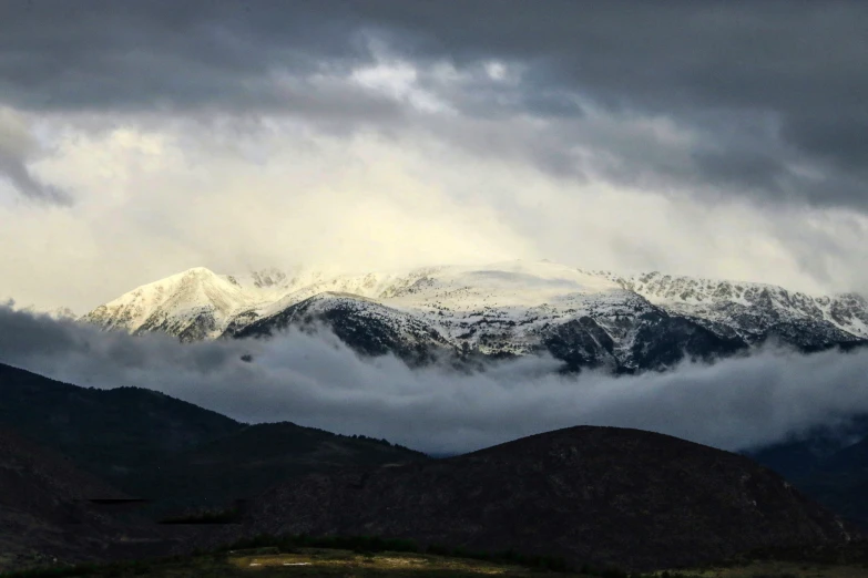 an airplane is flying over a mountain covered in clouds