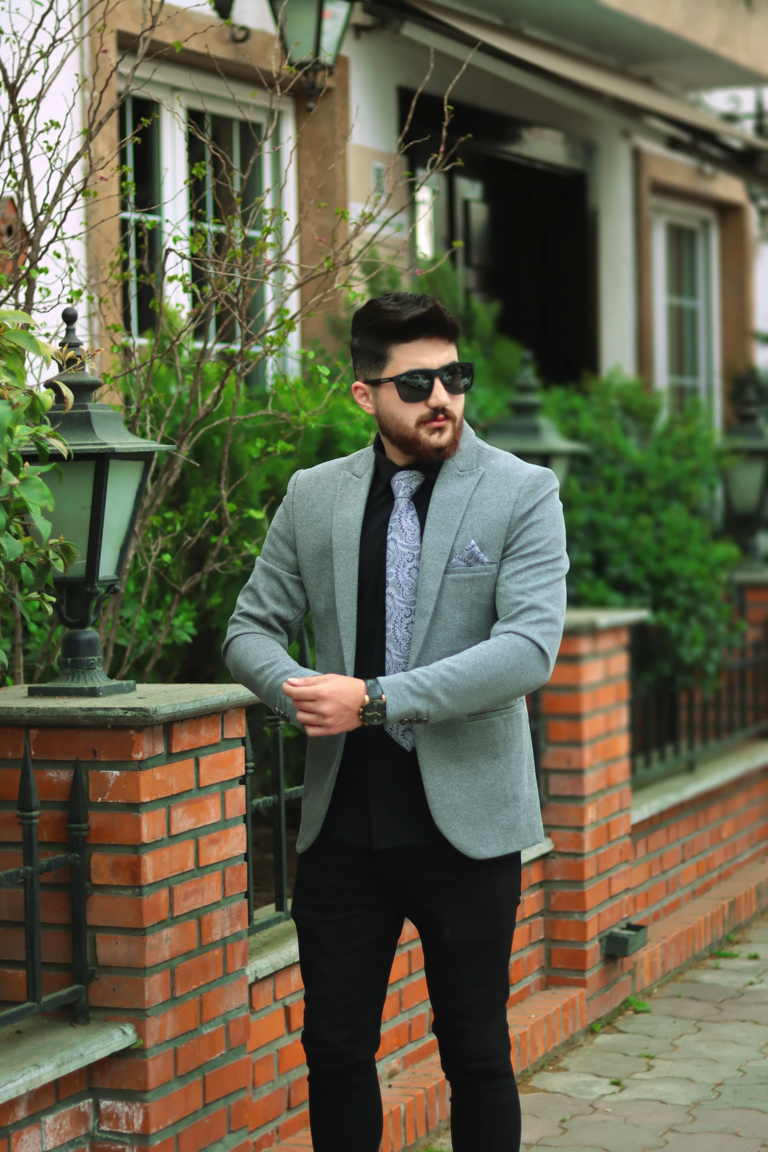 a man with sunglasses and a suit is leaning against a wall