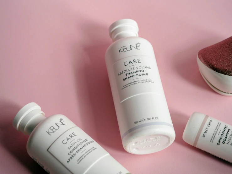 three bottles of skin care sit on a pink surface