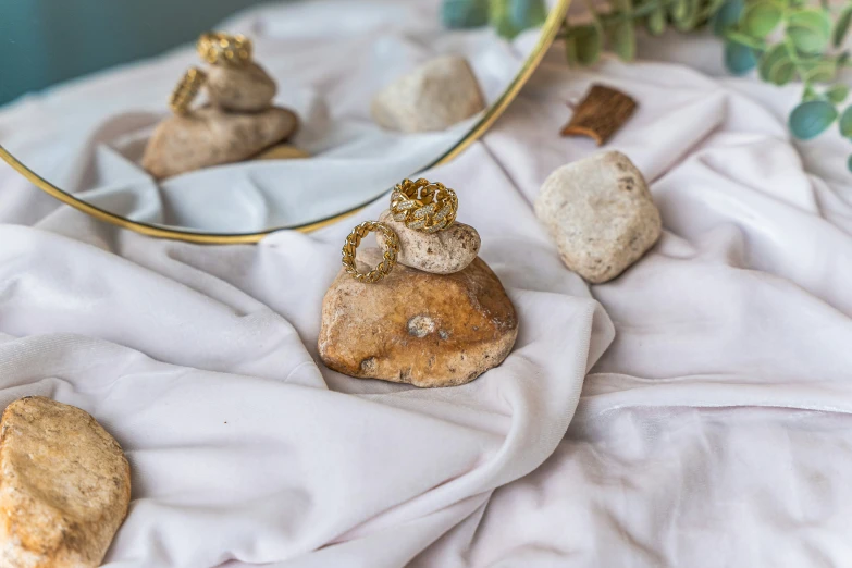 some small rocks and a vase sitting on a white blanket