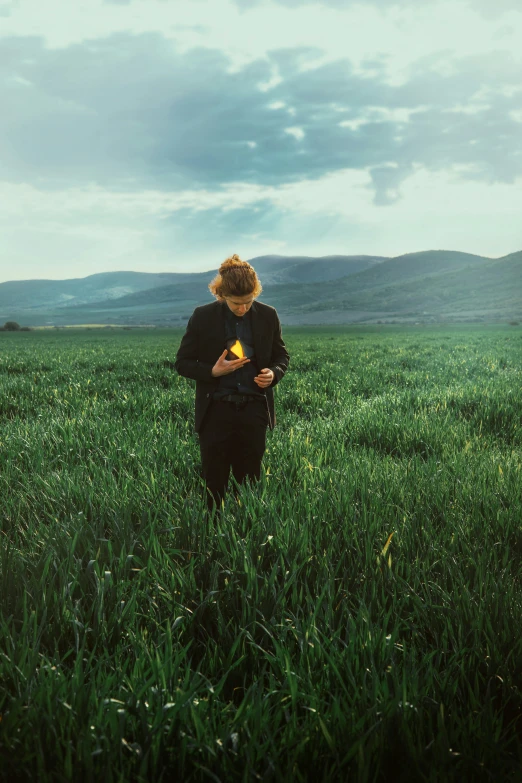 a woman standing in a grassy field with her hands folded