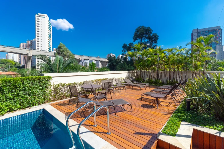 a wooden deck next to a pool and a cityscape