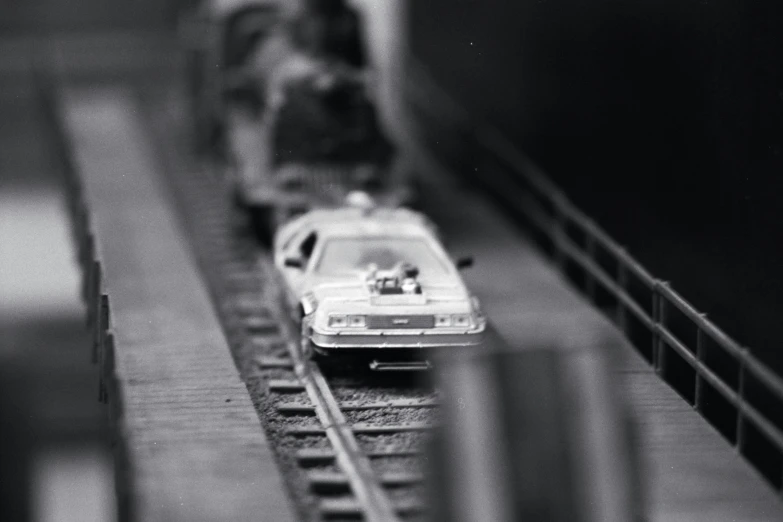 a toy train with a white car driving next to a smaller train