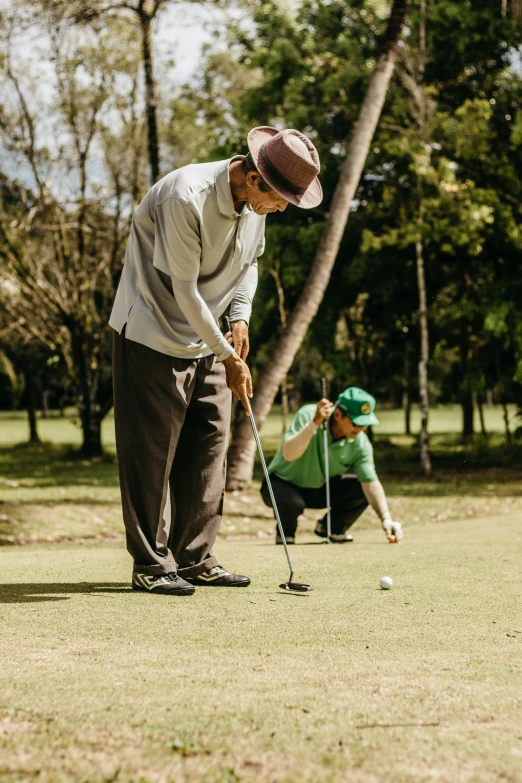 two men playing golf on the grass near trees