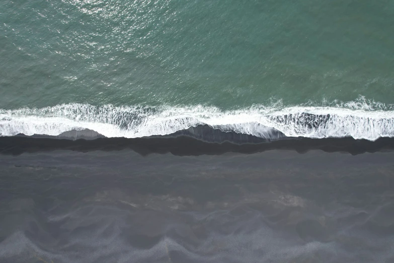 an aerial view of a sandy beach, with waves breaking against the sand