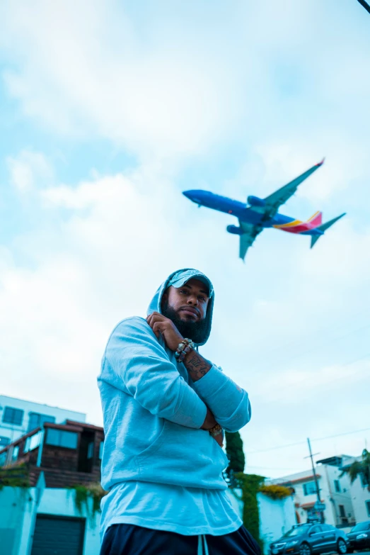 man in blue sweatshirt standing next to flying airplane