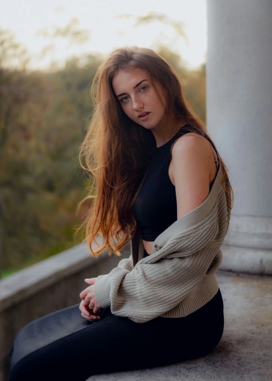 a girl with red hair is sitting on a column