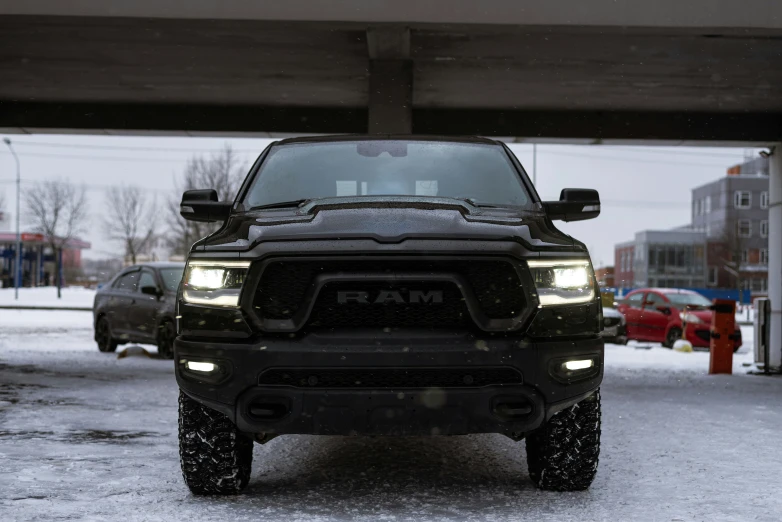 a black truck parked in the snow near some parked cars