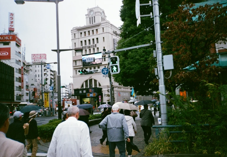 pedestrians on a street with buildings and trees in the background