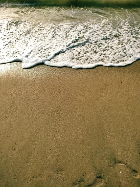 an ocean beach with waves coming in to the shore and footprints left in the sand