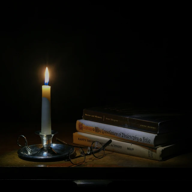 a lit candle sits on top of three books